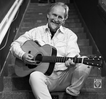 Affischbild för Drew Young. Leende man med en gitarr i famnen.