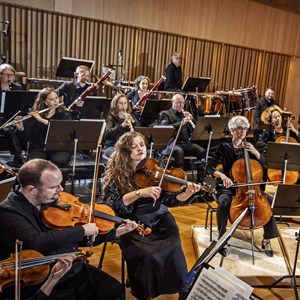 Affischbild för Jönköpings Sinfonietta. En orkester leds av en gestikulerande dirigent.