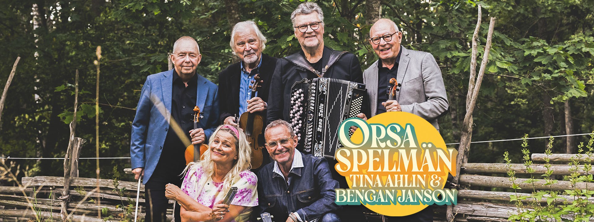 Affischbild för Orsa spelmän, Tina Ahlin & Bengan Janson. Fem manliga musiker och en kvinnlig musiker står framför en gärdsgård. 